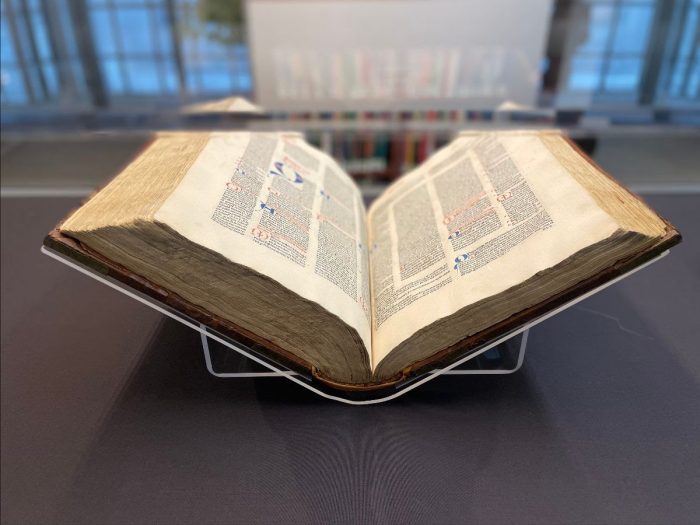 Image of Gratian's Decretum, a large book held open in a glass exhibit case