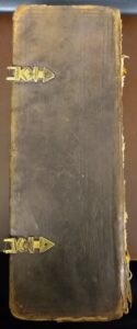 Long, narrow book with a brown binding and gold clasps