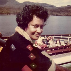 African american woman sitting near lake and mountains